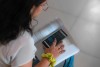 A femal presenting person uses ChatGPT on their phone while doing homework