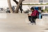 A male presenting student sits in the quad in front of the library scrolling their phone